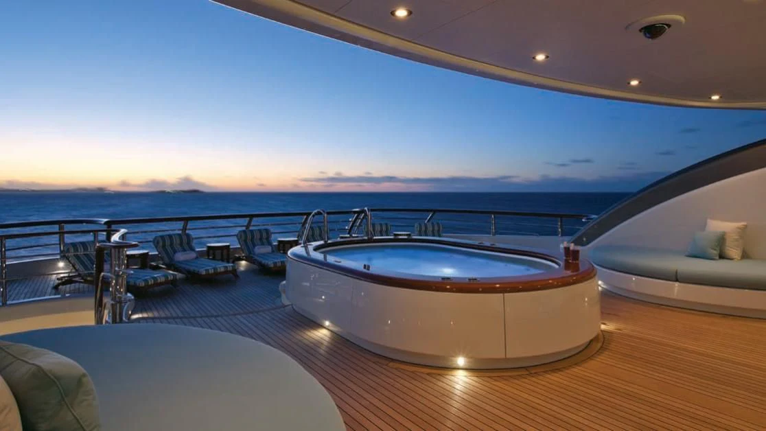 a large pool with a deck overlooking a beach and ocean aboard AQUILA Yacht for Sale