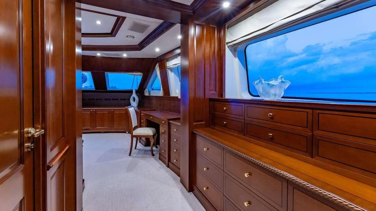 a room with a large window and a dresser with a chair and a television on it aboard NAMASTE Yacht for Sale