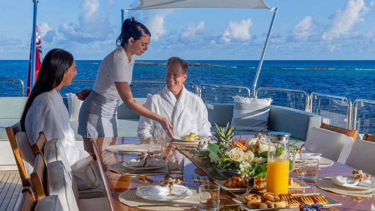 a man and woman sitting at a table with food on it aboard NAMASTE Yacht for Sale