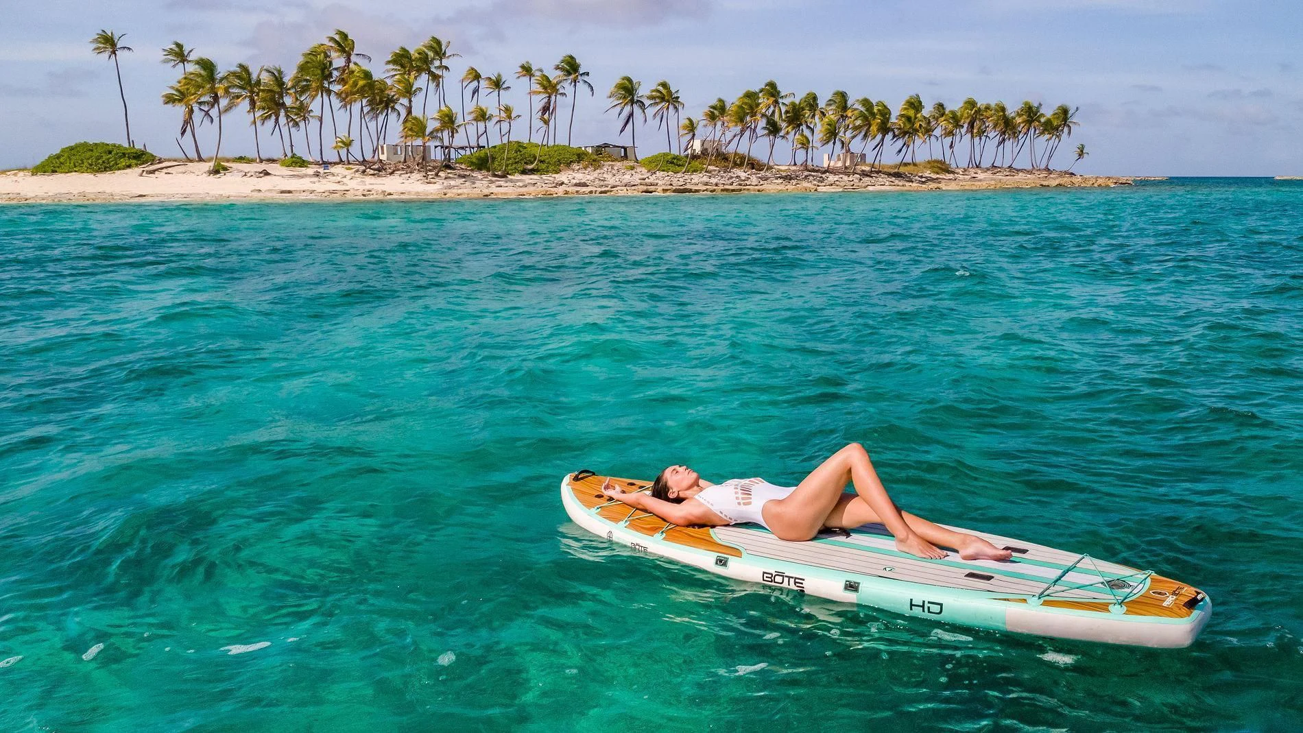 a person lying on a surfboard in the ocean aboard NAMASTE Yacht for Sale