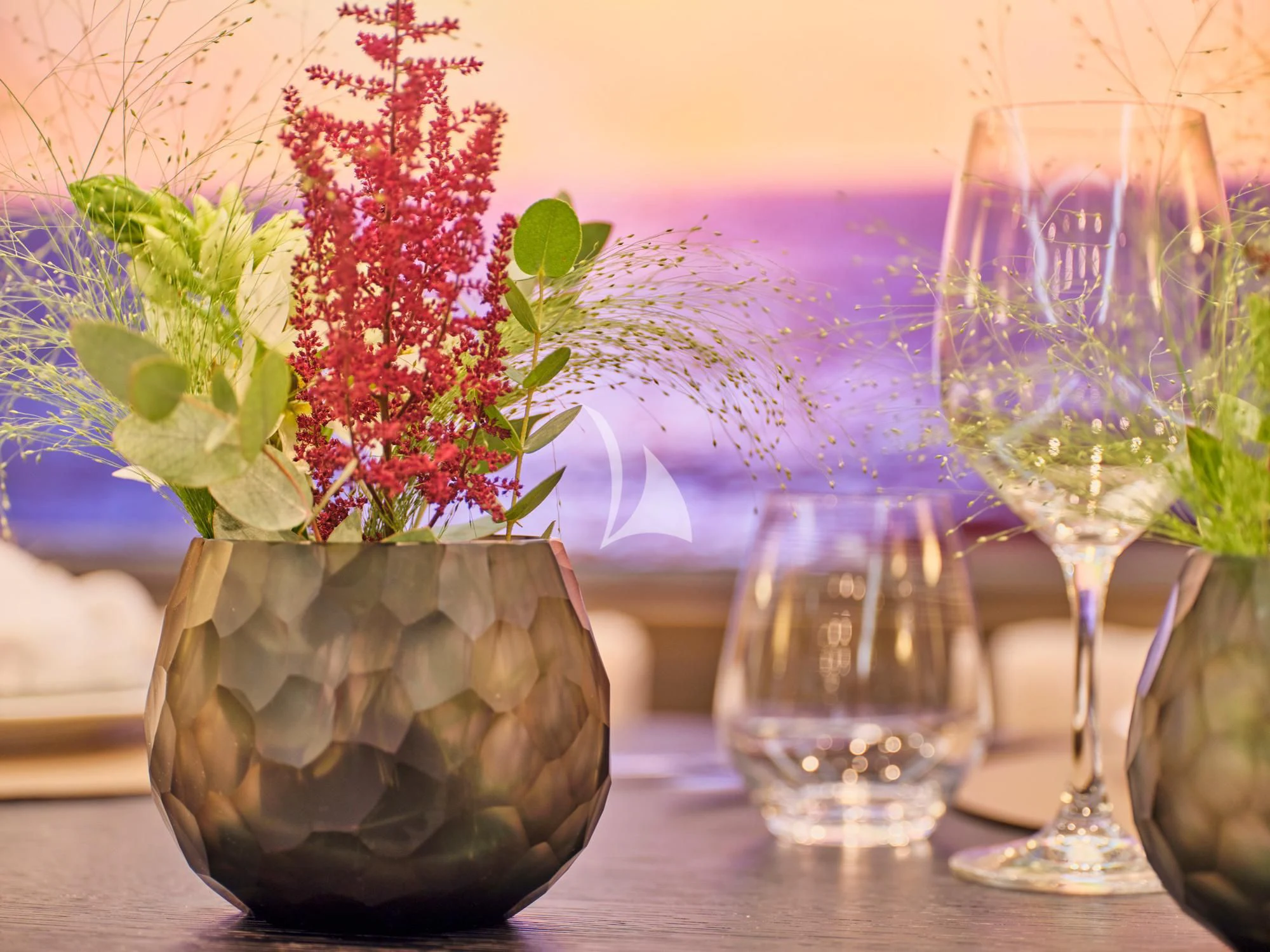 a vase of flowers next to a glass of wine aboard MAKANI II Yacht for Charter