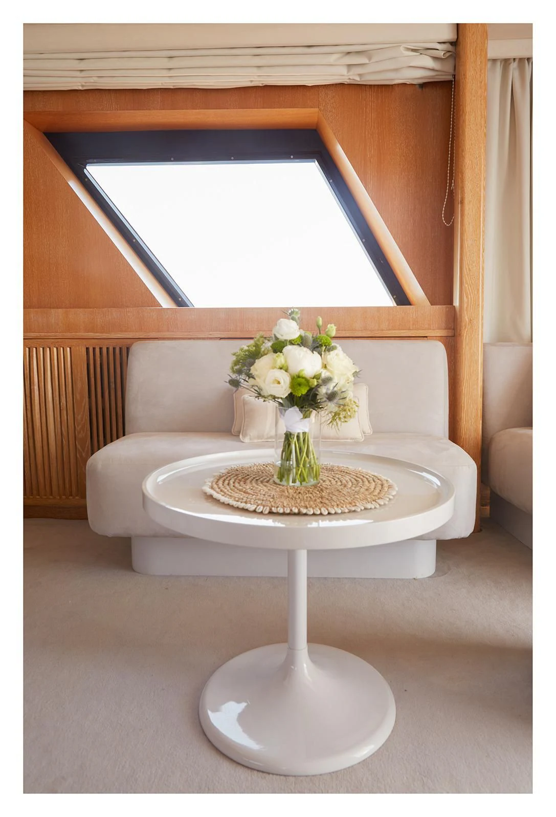 a white coffee table with a vase of flowers on it aboard SEA LADY II Yacht for Sale