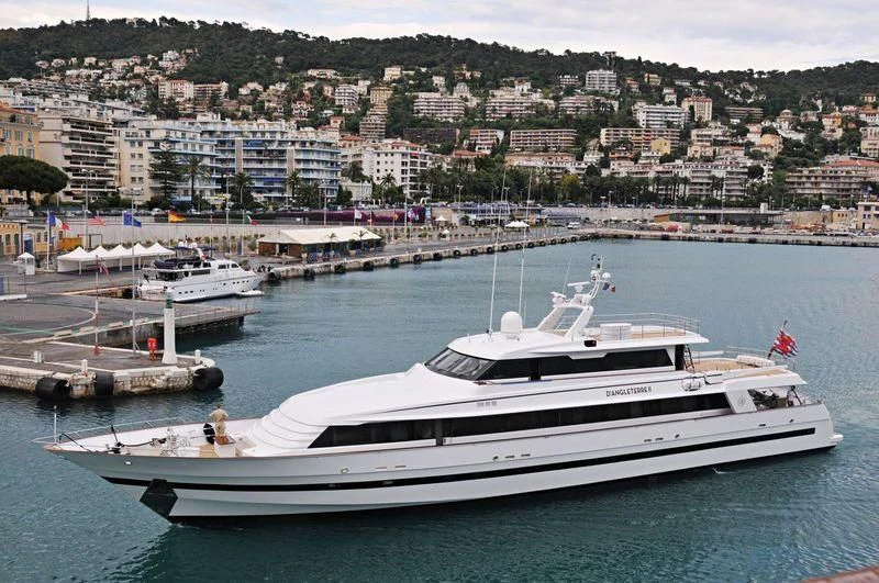 a large white yacht docked at a dock with a city in the background aboard SEA LADY II Yacht for Sale