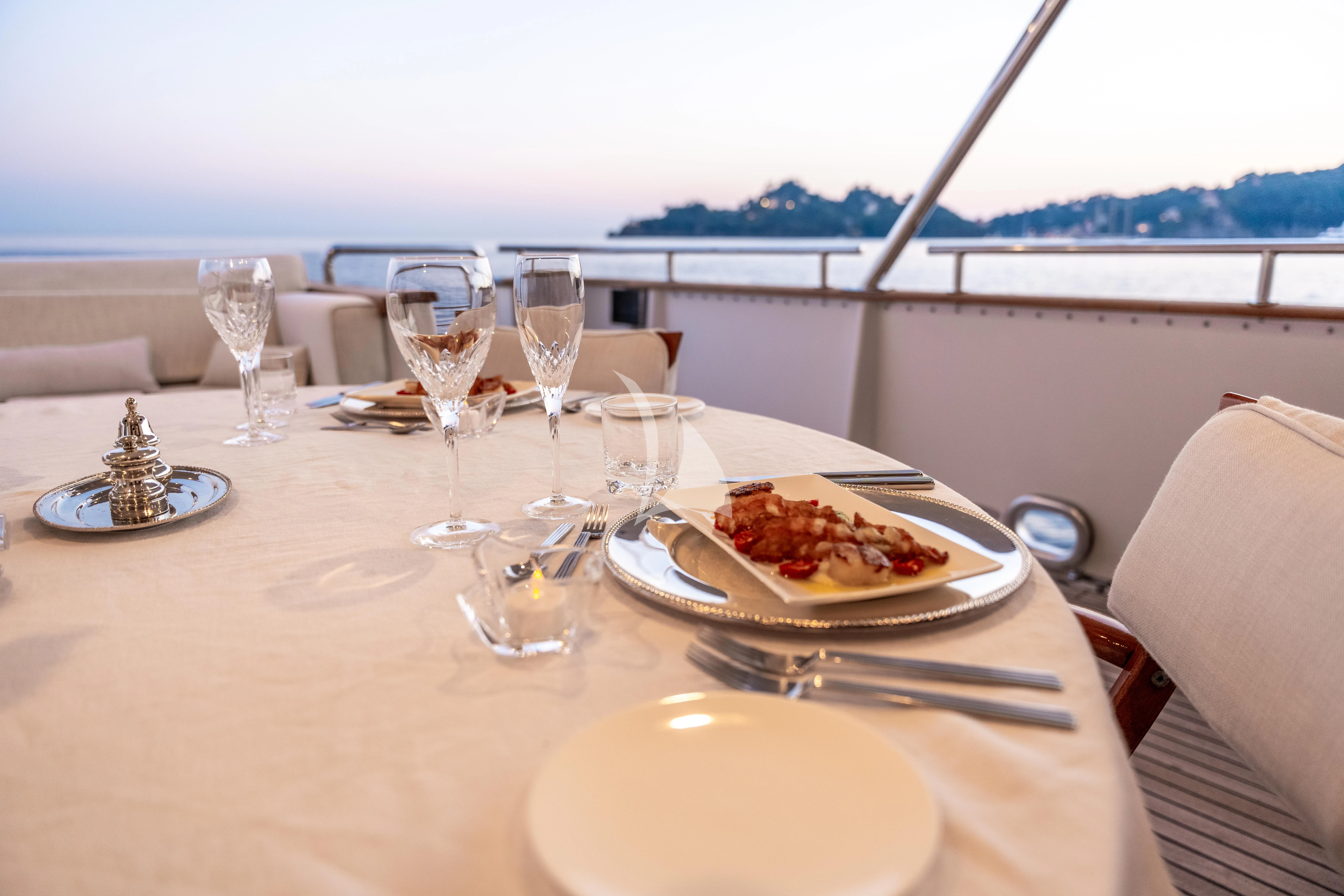 a table with food and wine glasses aboard SEA LADY II Yacht for Sale