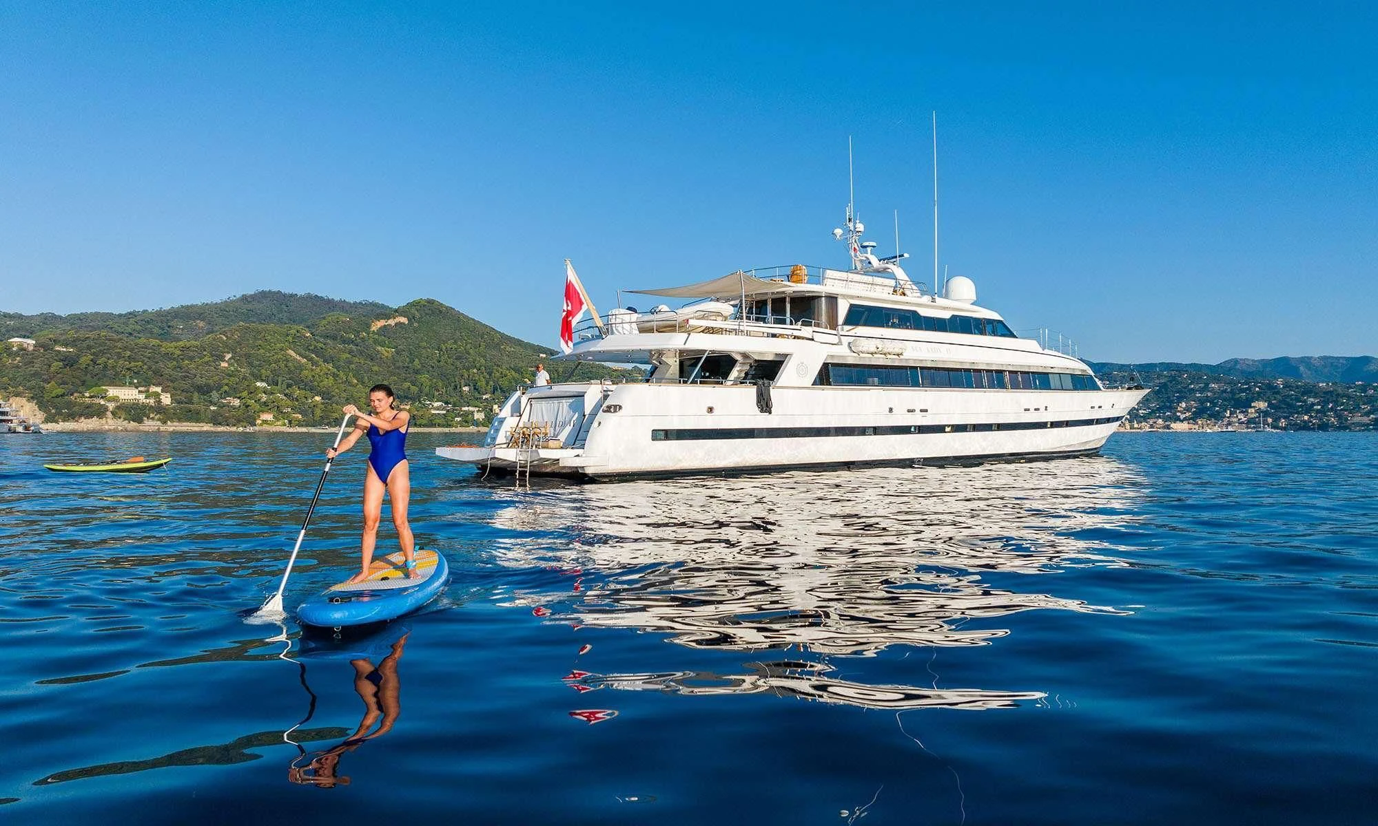 a person on a paddle board in front of a white boat aboard SEA LADY II Yacht for Sale