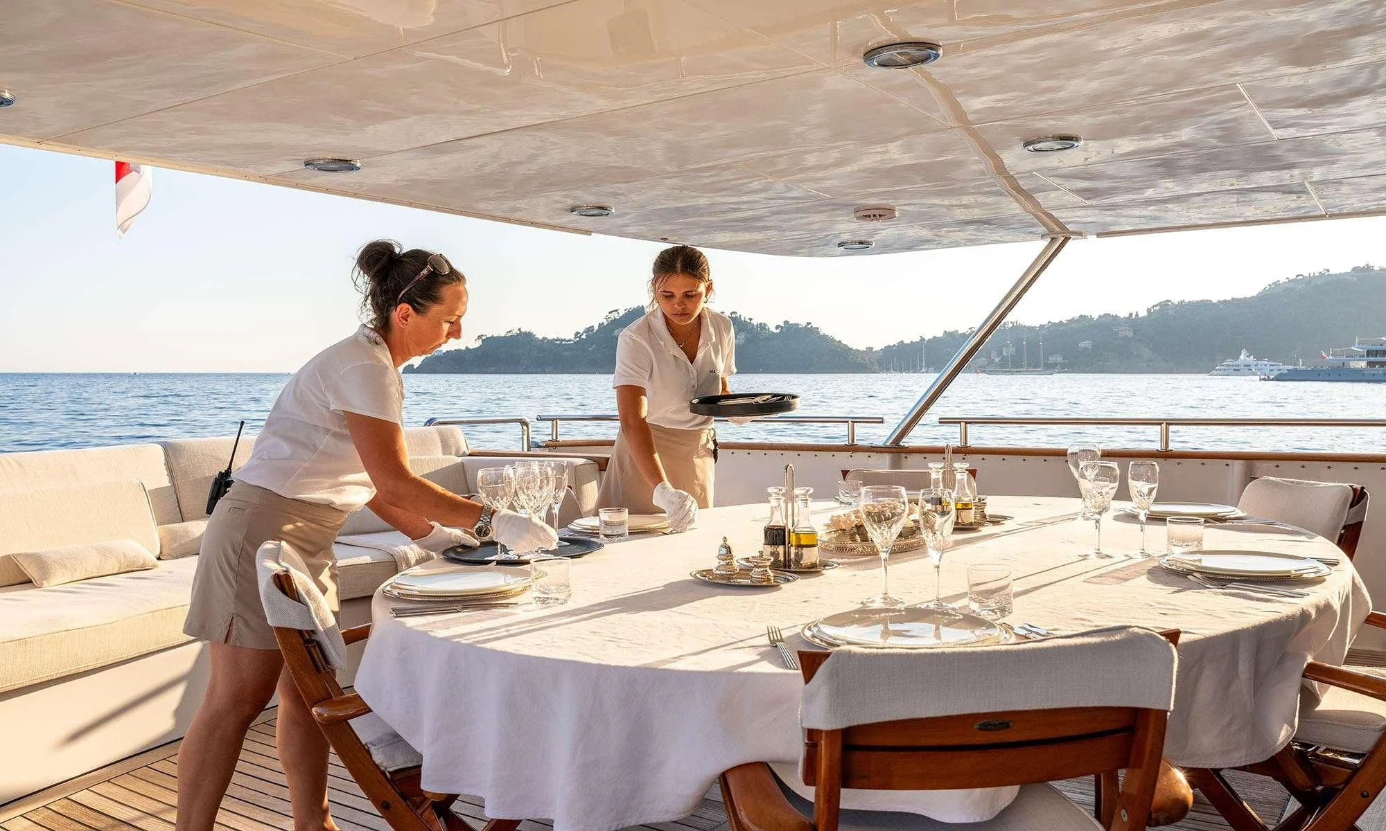 a couple of women sitting at a table with wine glasses and a person sitting at a table with aboard SEA LADY II Yacht for Sale