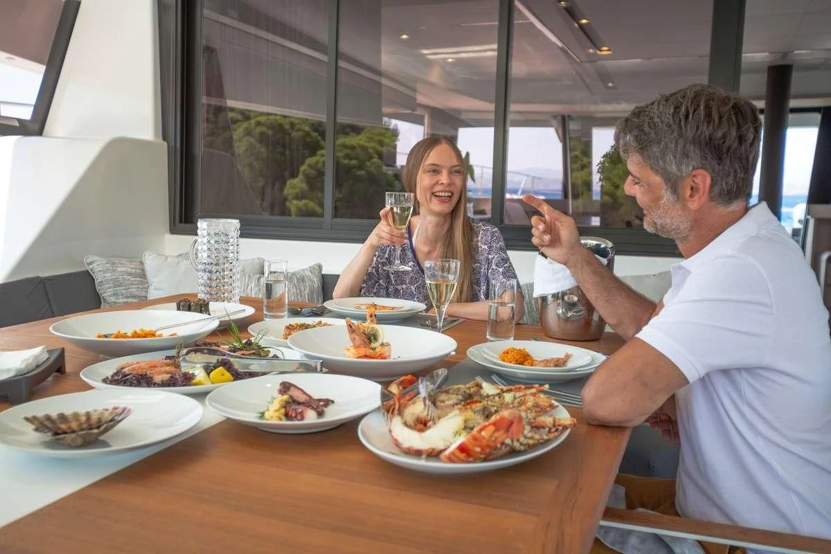a man and woman sitting at a table with food aboard MAJESTY OF GREECE Yacht for Charter