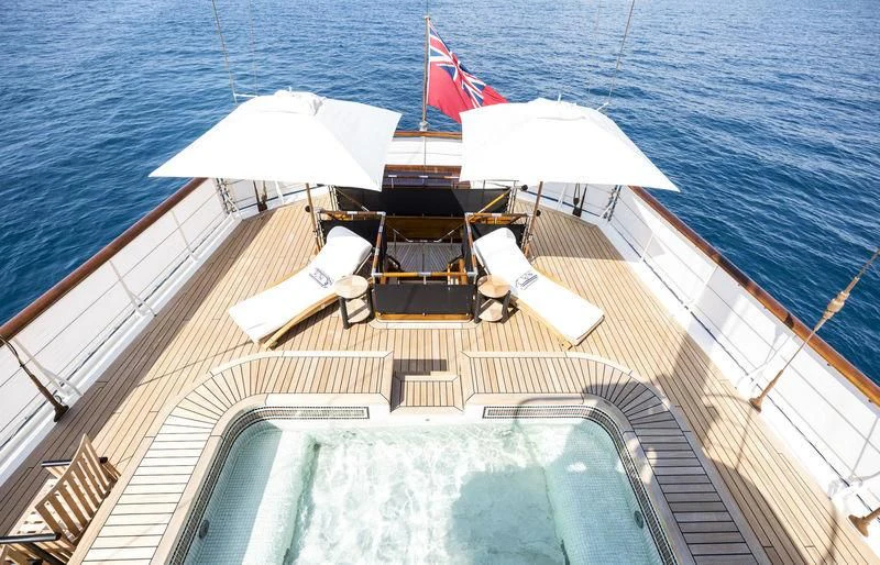 a deck with a large umbrella and a lounge chair on it aboard TALITHA Yacht for Sale