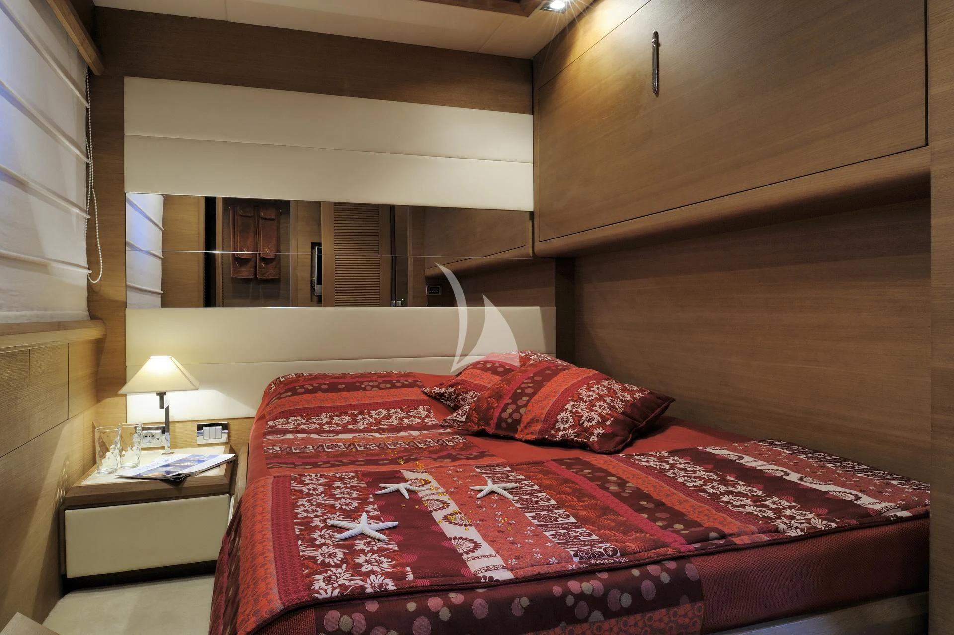 a bed with a red comforter aboard LEONARDO 98 Yacht for Sale