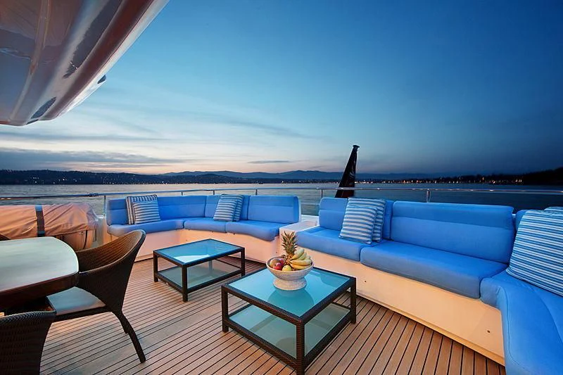 a living room with a large blue sofa and a table with a black chair and a blue sky aboard SIMA Yacht for Sale