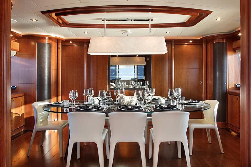 a large dining table with white chairs aboard SIMA Yacht for Sale