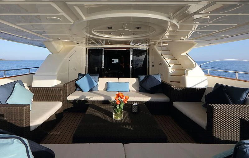 a room with couches and a table with flowers on it aboard SIMA Yacht for Sale