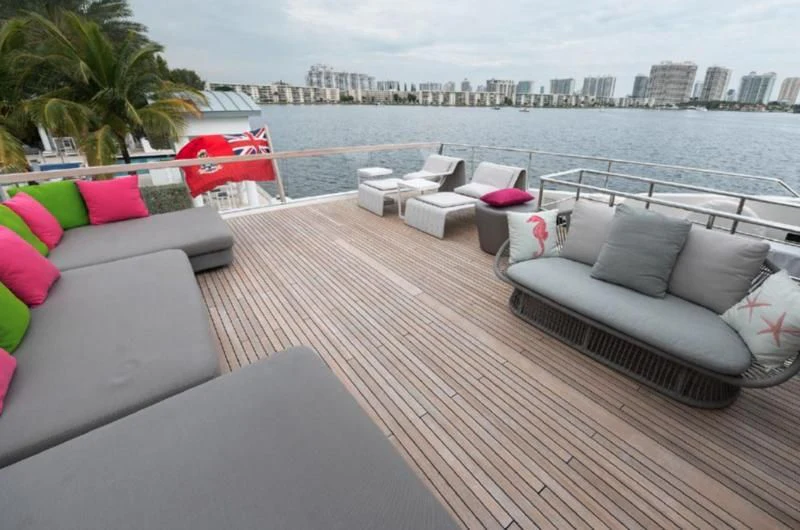 a deck with couches and chairs on it by the water aboard RAYEN Yacht for Sale