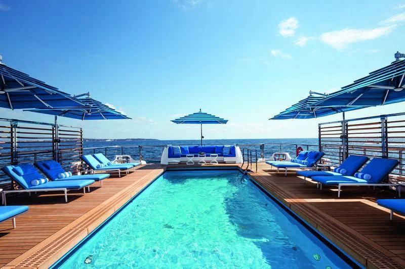 a pool with lounge chairs on the deck and a pool of water aboard SEASENSE Yacht for Sale