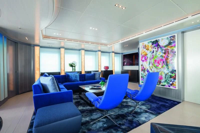 a room with blue couches and a table aboard SEASENSE Yacht for Sale