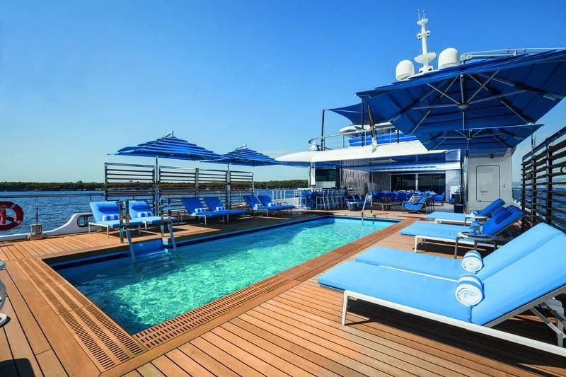 a deck with a pool and a large ship in the background aboard SEASENSE Yacht for Sale