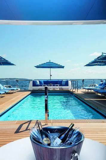 a pool with a umbrella and a boat in the background aboard SEASENSE Yacht for Sale