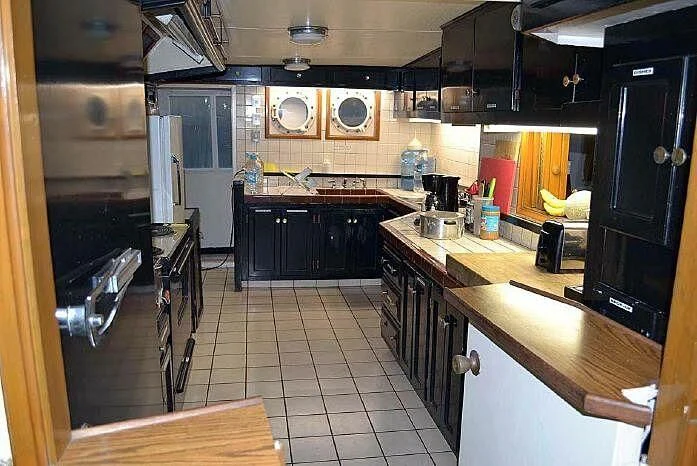 a kitchen with black appliances aboard ROSE Yacht for Sale