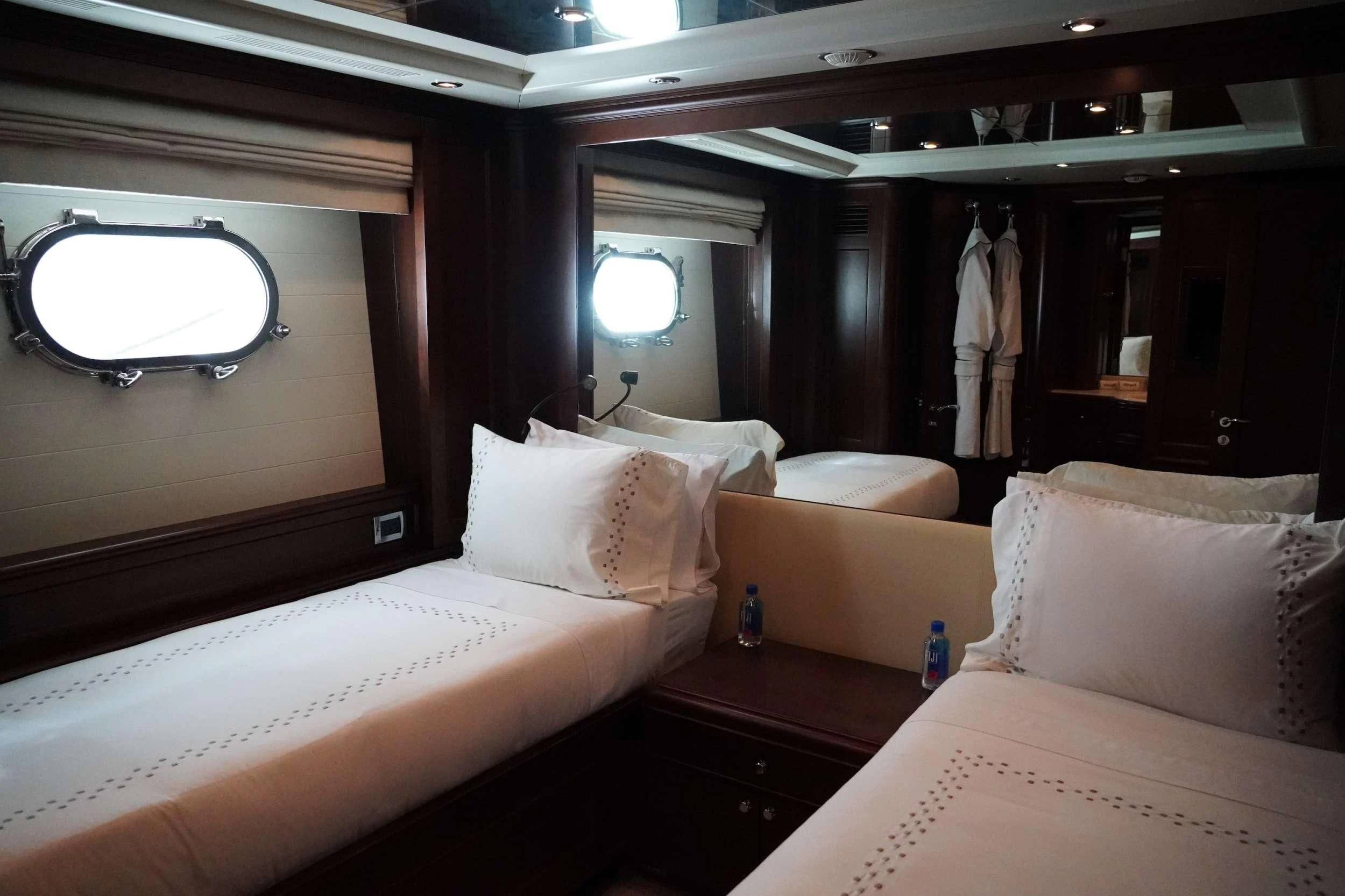 a room with beds and a mirror aboard CRISTOBAL Yacht for Charter