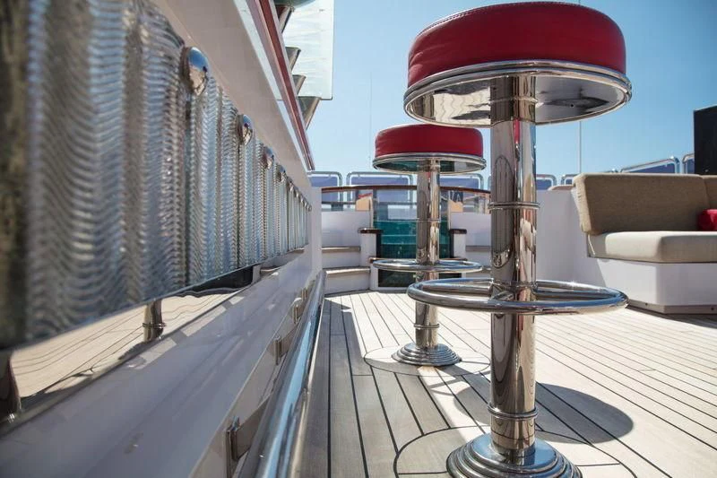 a deck with a chair and a table and a red umbrella aboard CODE 8 Yacht for Sale