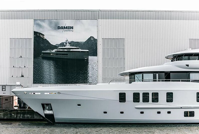 a large white boat next to a smaller boat aboard SYNTHESIS Yacht for Sale