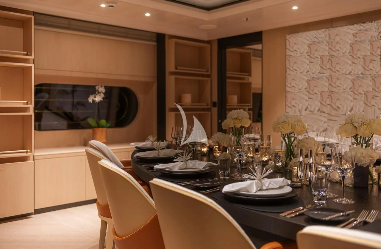 a dining table with plates and glasses aboard SYNTHESIS Yacht for Sale