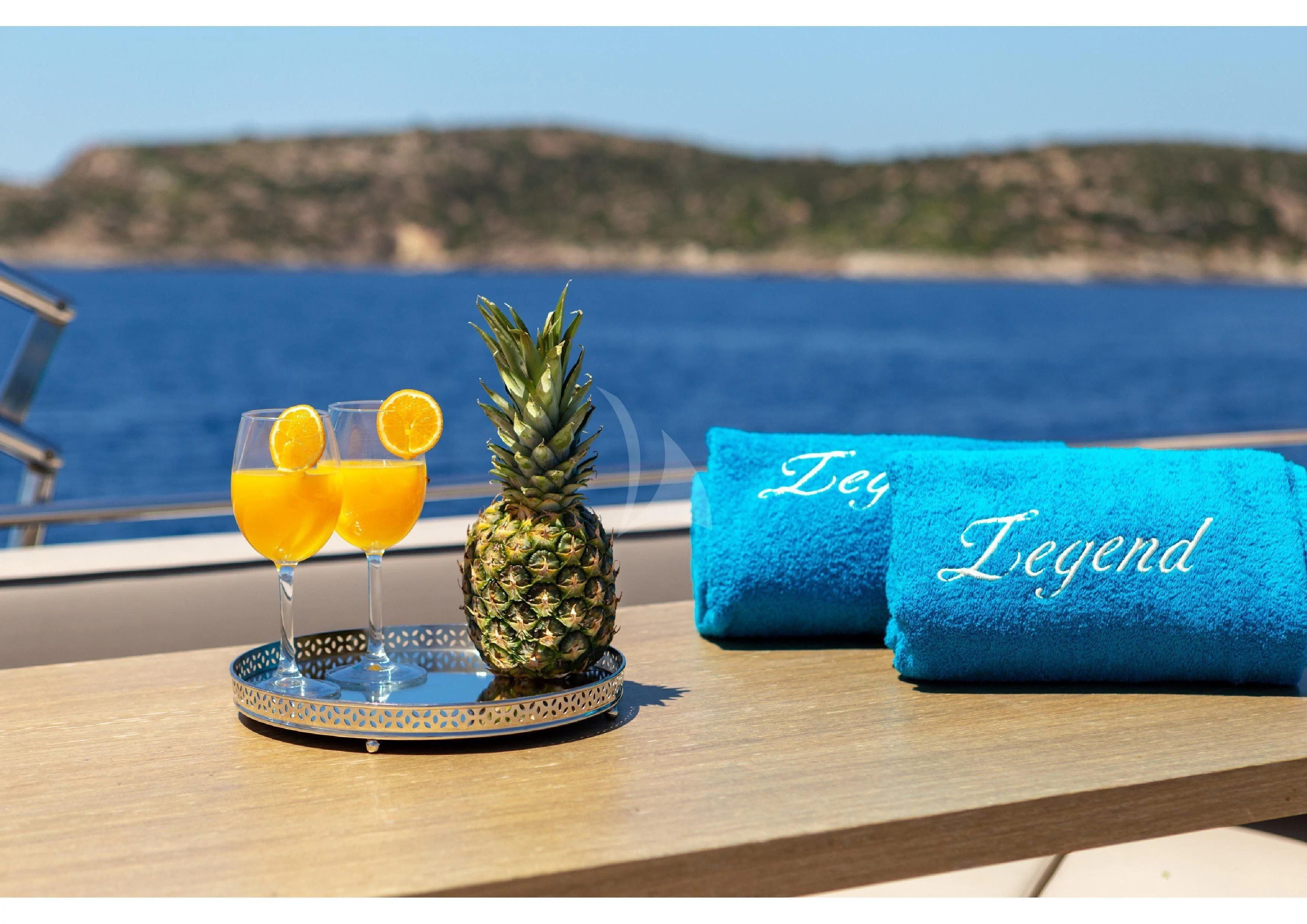 a table with a drink and a book on it aboard LEGEND Yacht for Sale