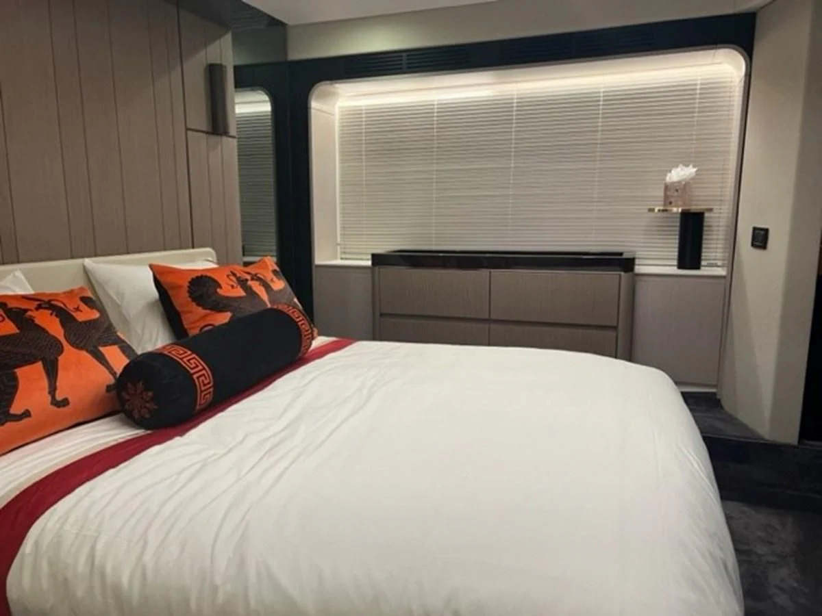 a bed with a white sheet and orange and red pillows aboard SOLSTICE Yacht for Sale