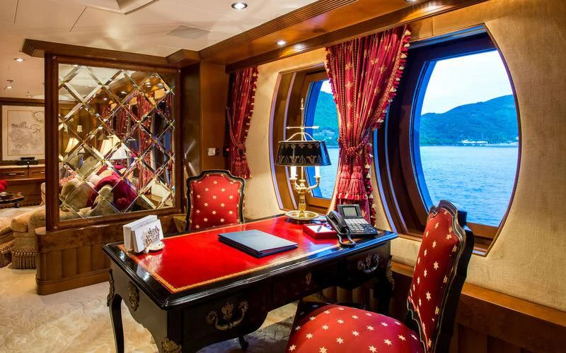 a table with a red cloth on it and a red chair in front of it aboard HARMONY Yacht for Sale