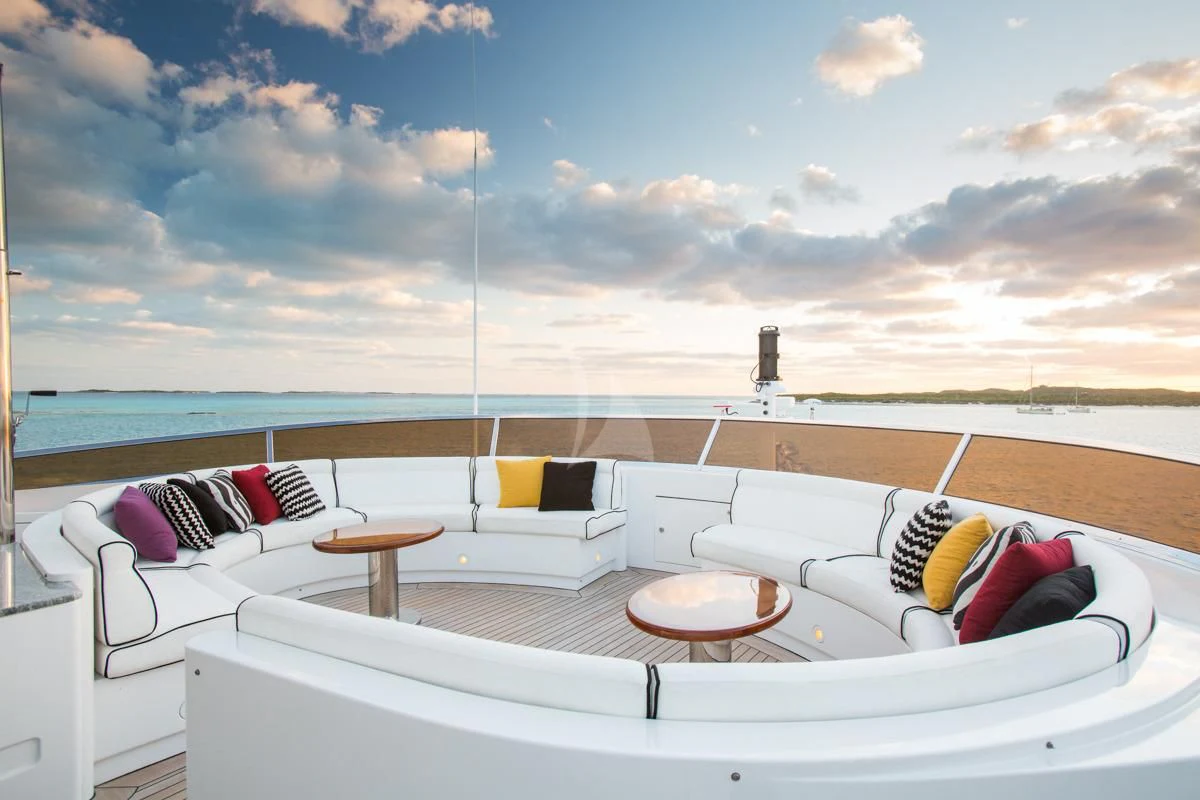 a bed and a table on a balcony overlooking a beach aboard CHECKMATE Yacht for Charter