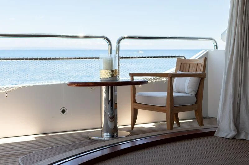 a glass table with a glass of wine on a balcony overlooking the ocean aboard CHECKMATE Yacht for Charter