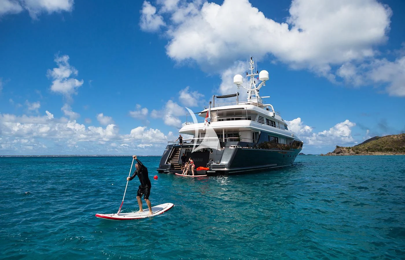a person on a paddle board next to a boat in the water aboard MARIU Yacht for Sale