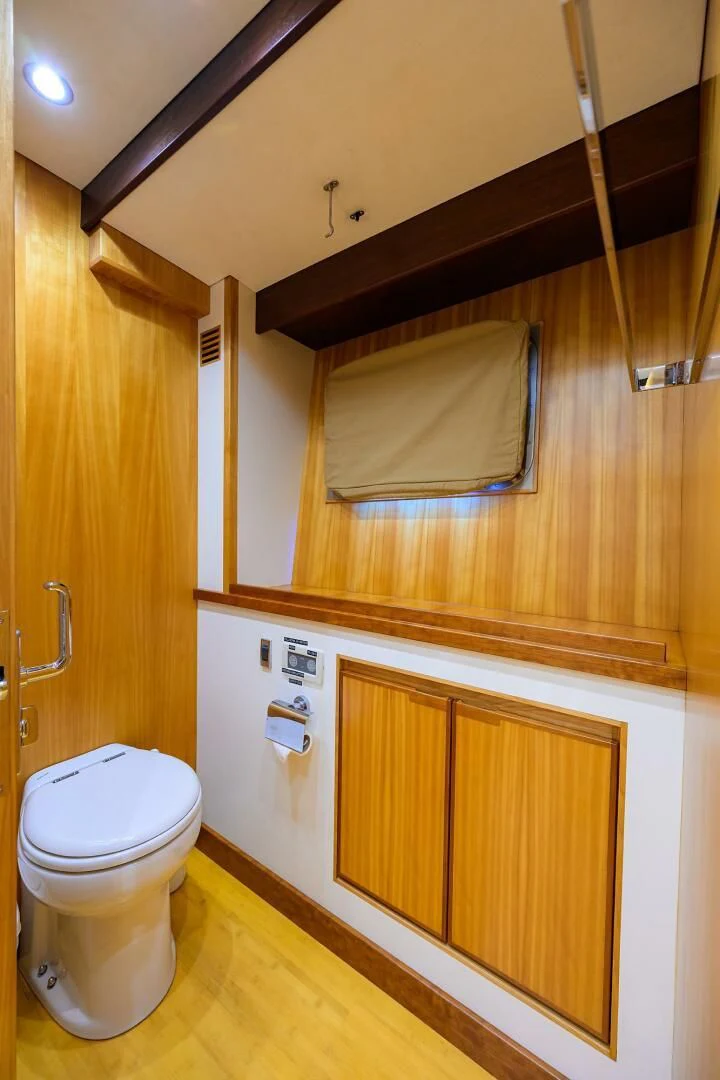 a bathroom with a toilet and wooden cabinets aboard ELECTRA Yacht for Sale