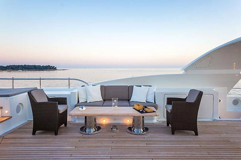 a room with a couch and a table and chairs on a deck aboard THEOLINA Yacht for Sale