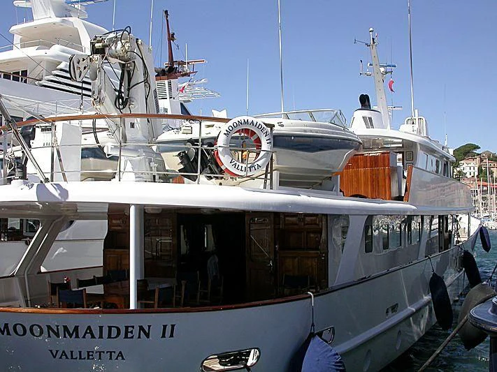 a boat docked in a harbor with HMS M33 in the background aboard TRAFALGAR Yacht for Sale