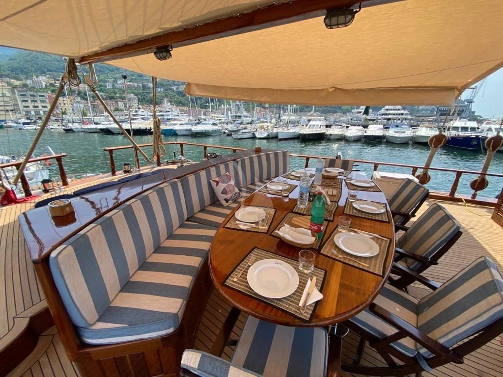 a table with plates and chairs on it next to a boat aboard MYRA Yacht for Sale