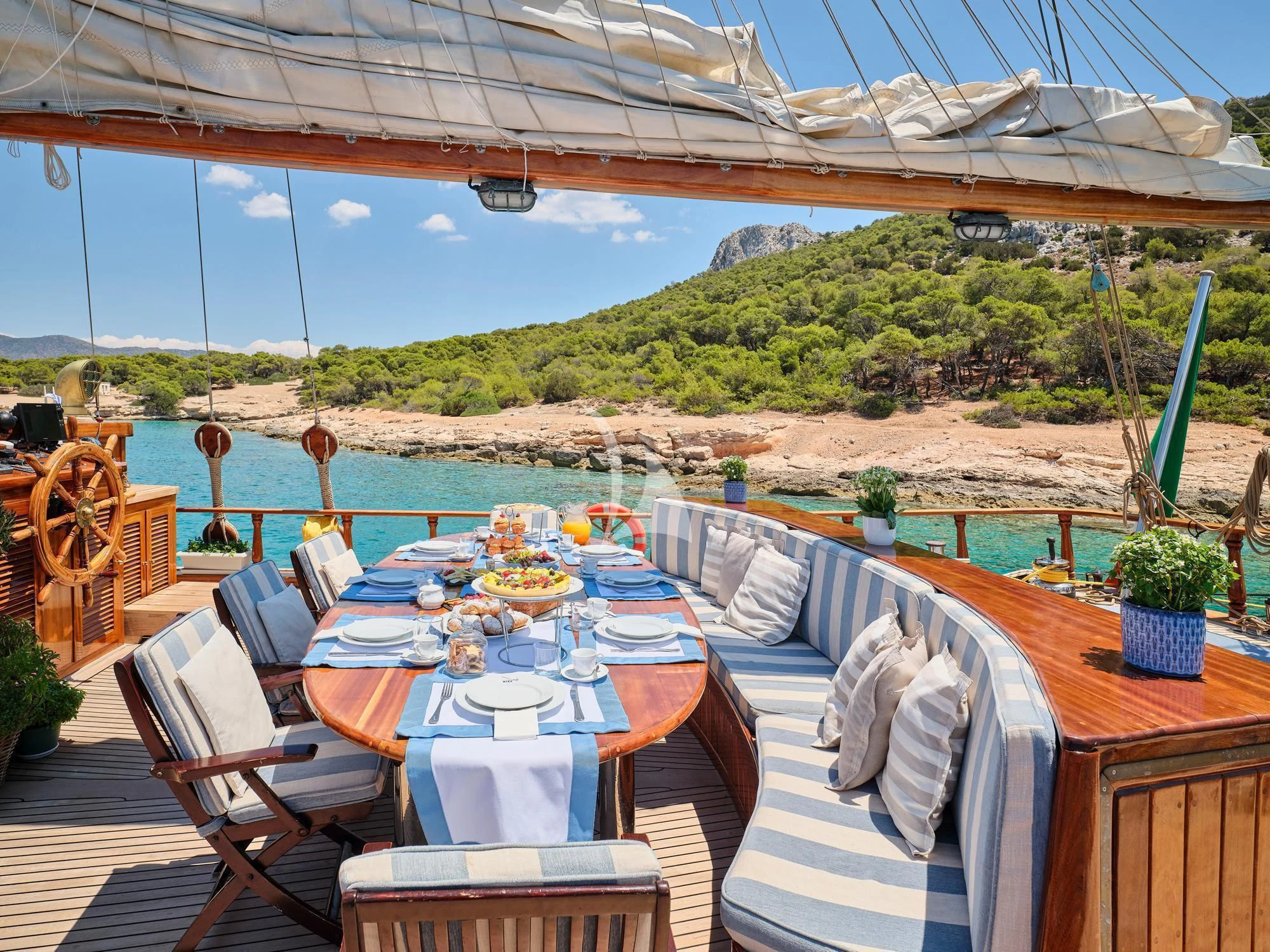 a table set for a meal on a deck overlooking a lake aboard MYRA Yacht for Sale