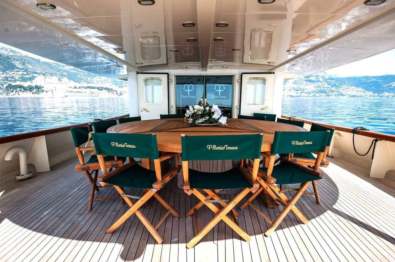 a table with green chairs on a deck with a view of the ocean aboard MARIA TERESA Yacht for Sale