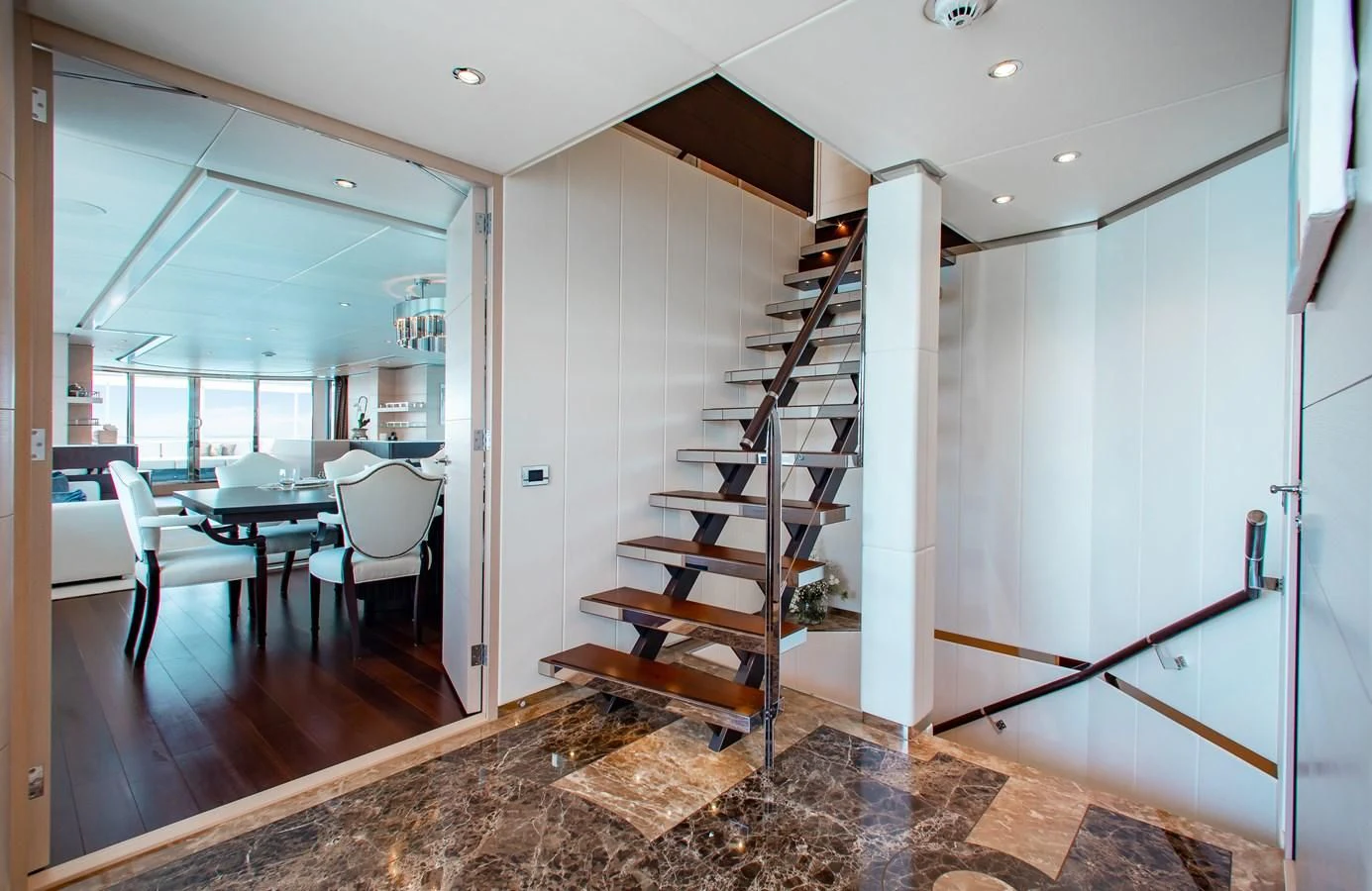 a room with a staircase and a table and chairs aboard LADY L Yacht for Charter
