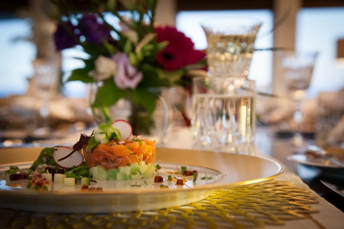 a table with a plate of food and flowers aboard LADY L Yacht for Charter