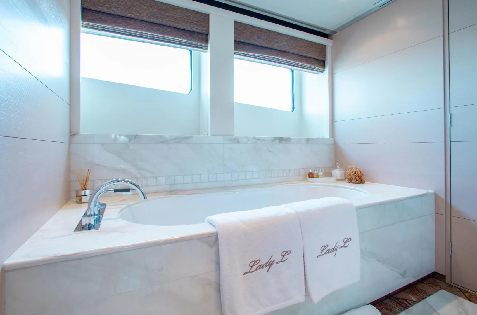 a bathtub with a sink and a window aboard LADY L Yacht for Charter