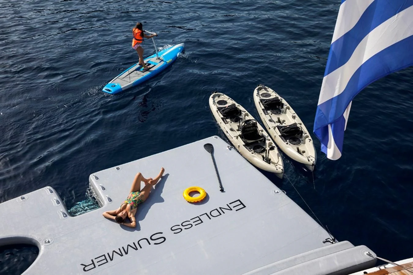 a person on a boat with a sail and a person on a surfboard aboard ENDLESS SUMMER Yacht for Sale
