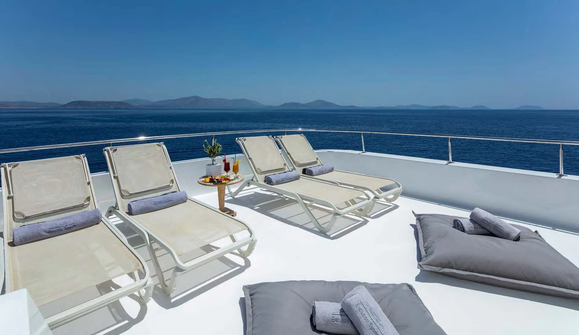 a room with a large bed and a table on the deck aboard ENDLESS SUMMER Yacht for Sale