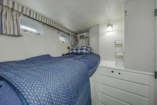 a bedroom with a bed and a dresser aboard LADY FAYE Yacht for Sale