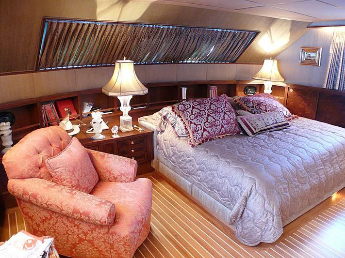 a bed with a blue comforter and a brown chair in a room with a large mirror and aboard C SIDE Yacht for Sale