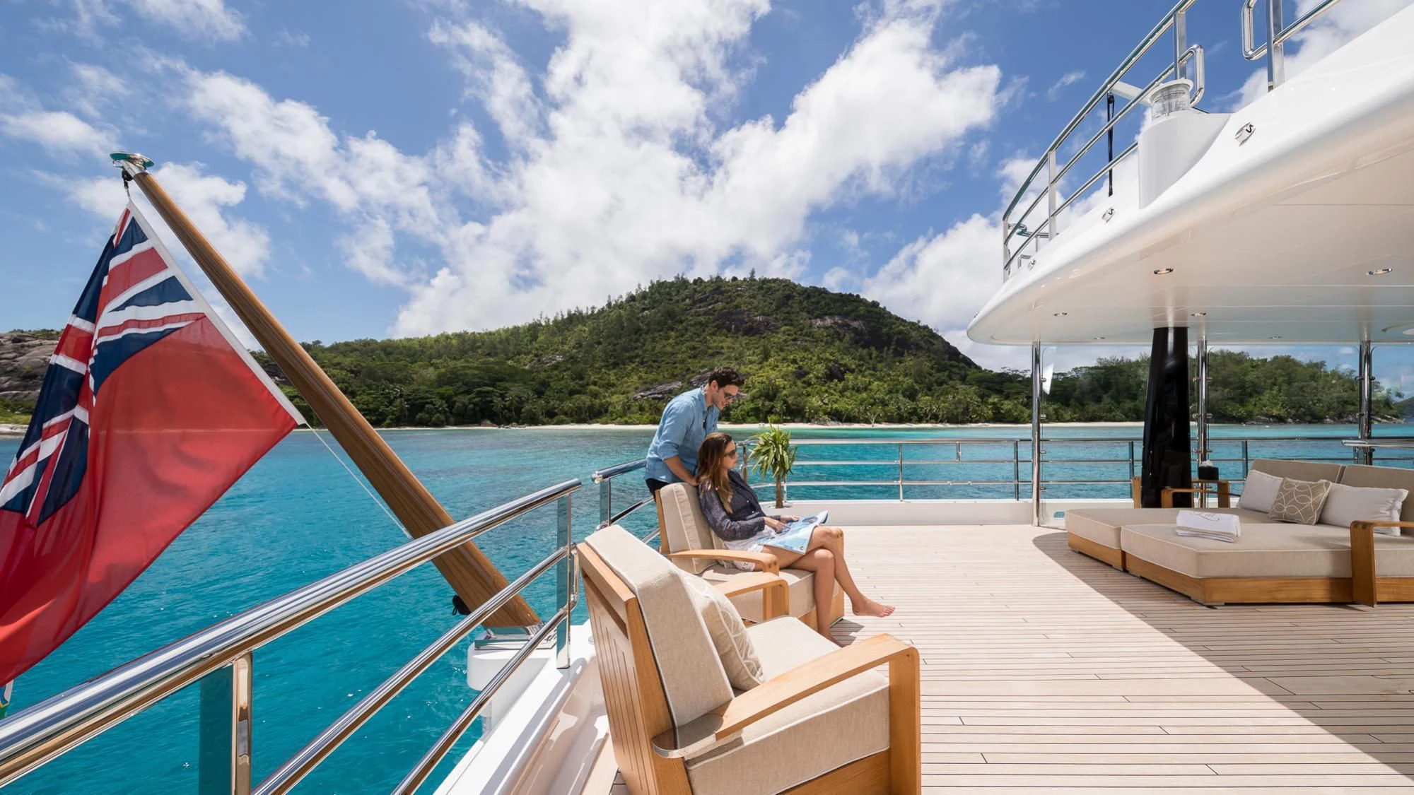 a couple sitting on a lounge chair on a deck overlooking the ocean aboard AMIGOS Yacht for Charter