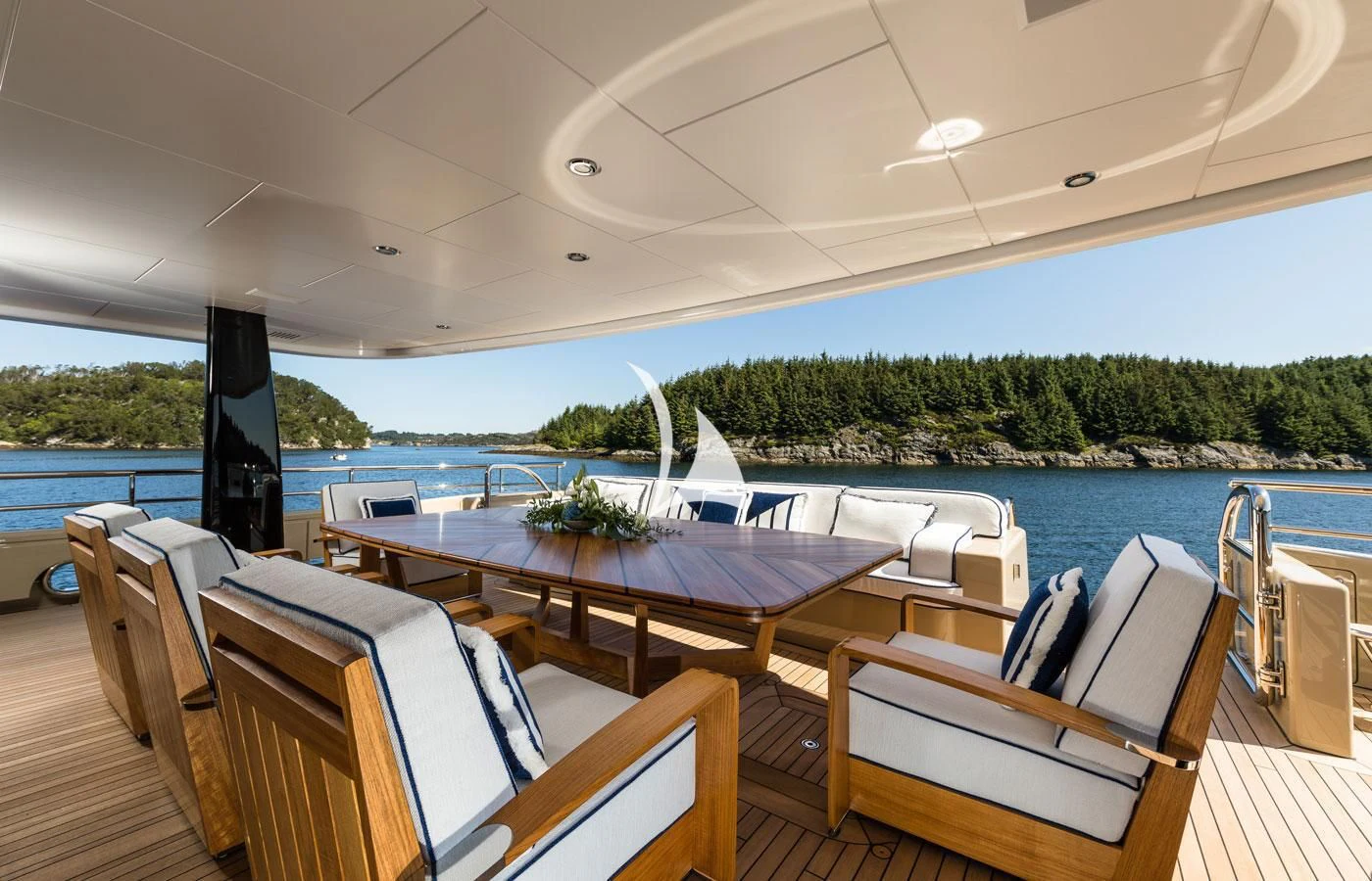 a large outdoor table with chairs and a large body of water in the background aboard AMIGOS Yacht for Charter