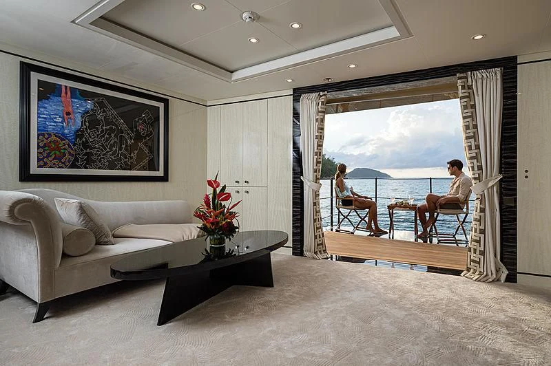 a person sitting on a couch next to a table and a large window aboard AMIGOS Yacht for Charter