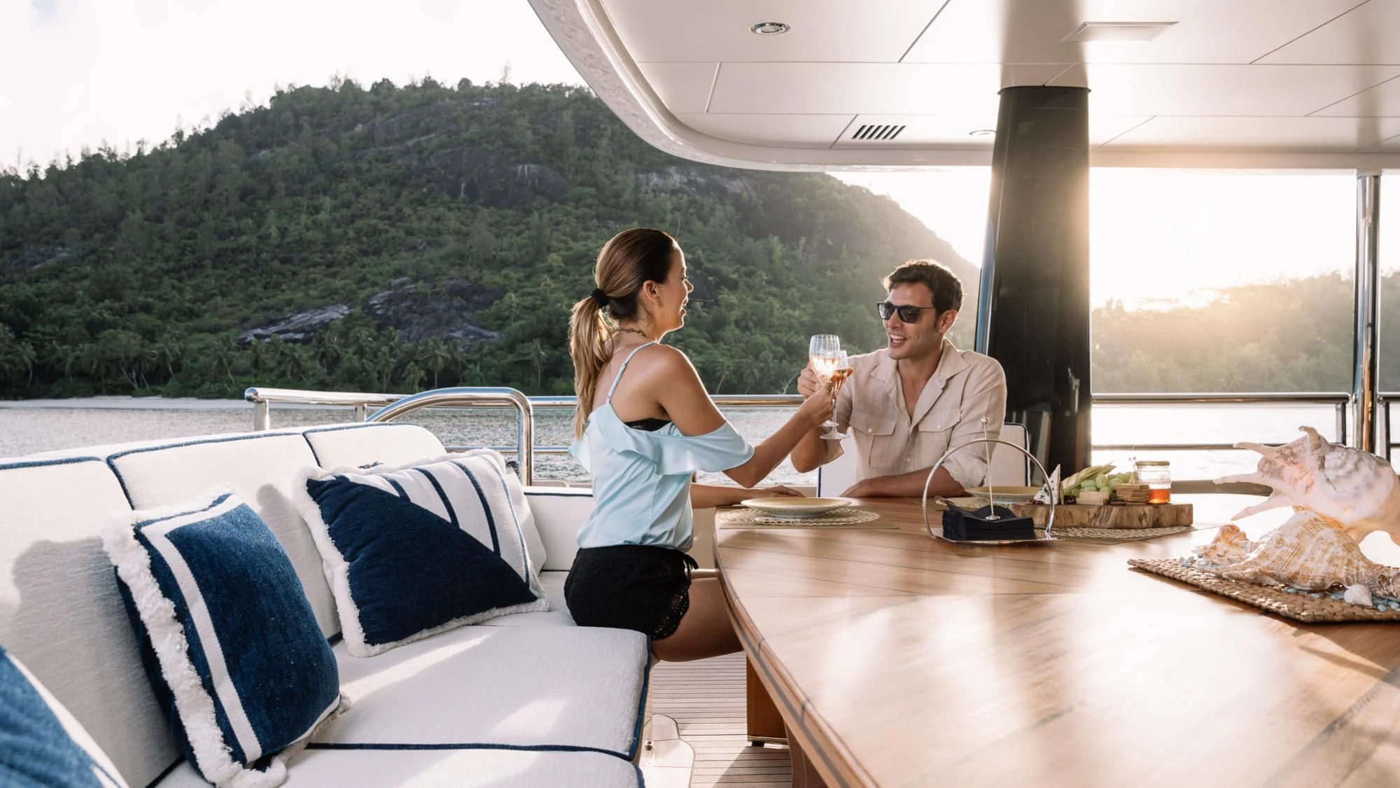 a man and a woman sitting at a table with food and drinks on it aboard AMIGOS Yacht for Charter