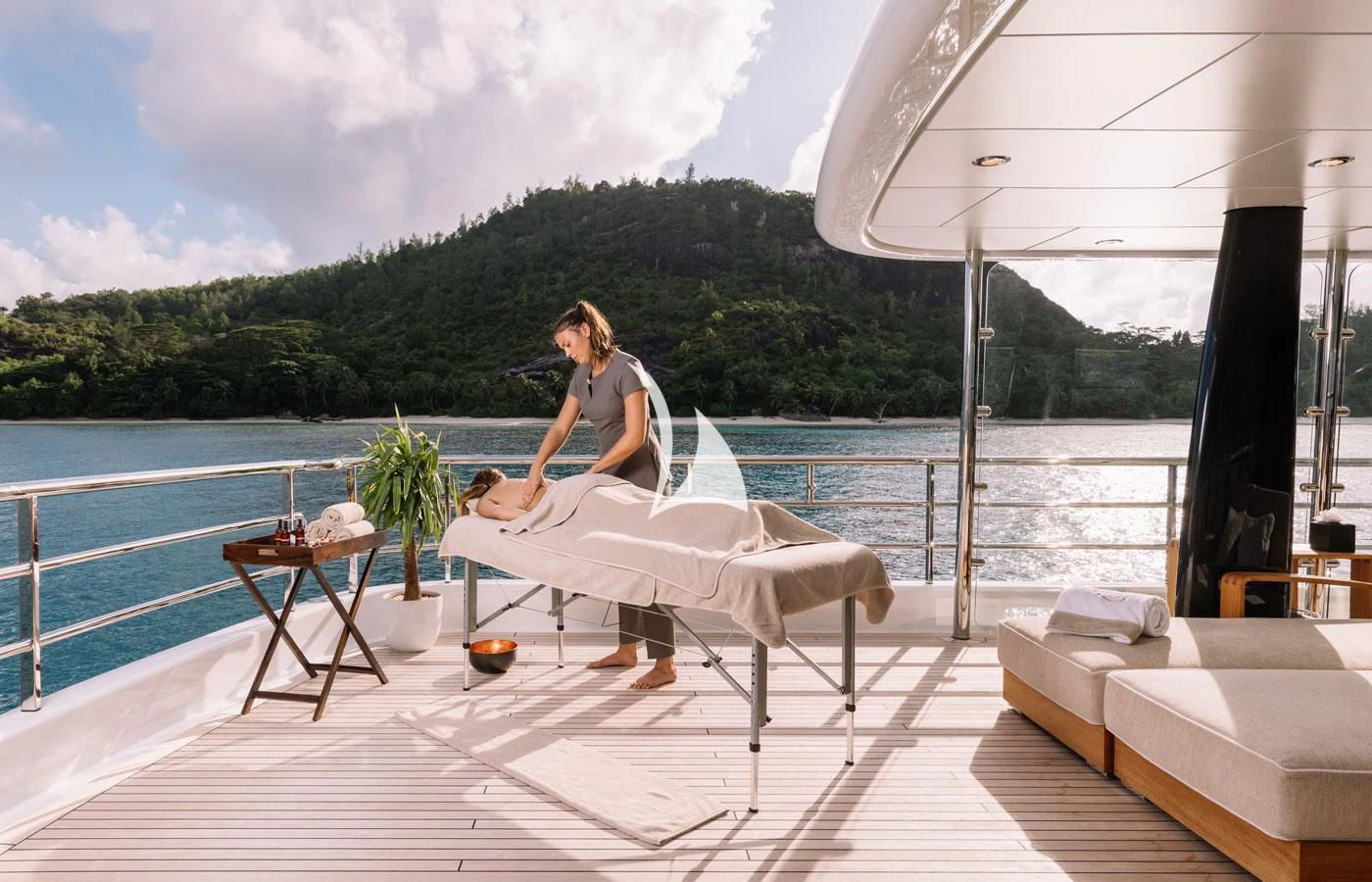 a person sitting on a lounge chair on a deck by a body of water aboard AMIGOS Yacht for Charter